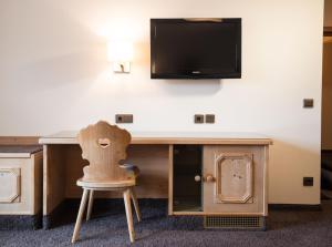 a desk with a chair and a tv on a wall at Landgasthof Weisses Lamm in Engelthal