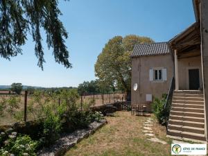 a building with a staircase next to a yard at Gîte Le Cayrou in Saint-Just-sur-Viaur