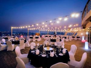 a banquet hall with tables and white chairs and lights at Queen Elizabeth 2 Hotel in Dubai