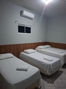 a room with three beds and a window at Hotel e Pousada REQUINTTE in Parnaíba