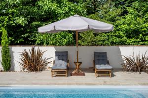 two chairs and an umbrella next to a swimming pool at La Demeure du Bord'Ô in Lagruère