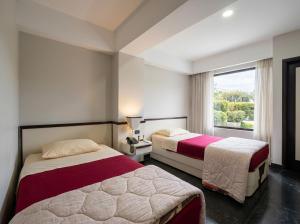 two beds in a hotel room with a window at Hotel Camino Real Valera in Valera
