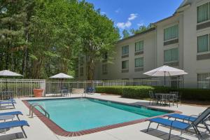 a swimming pool with chairs and umbrellas in front of a building at SpringHill Suites by Marriott Atlanta Alpharetta in Alpharetta