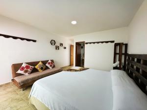 a bedroom with a large white bed and a couch at The Rock House Eco in San Andrés