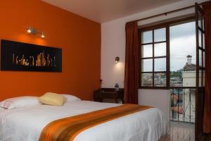 a bedroom with an orange wall with a bed and a window at Hotel Casa Ecuatreasures Centro Historico in Quito