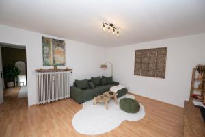 a living room with a green couch and a table at Green Mango - City Apartment mit Balkon in Mürzzuschlag