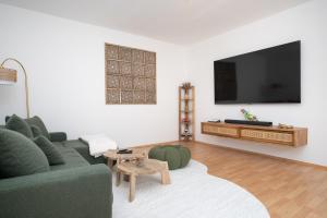 a living room with a green couch and a flat screen tv at Green Mango - City Apartment mit Balkon in Mürzzuschlag