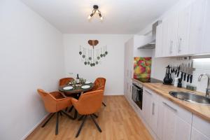 a kitchen with a table and chairs and a sink at Green Mango - City Apartment mit Balkon in Mürzzuschlag
