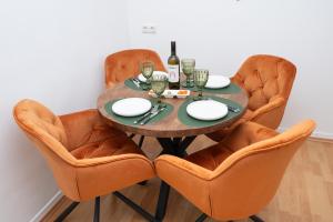 a dining room table with orange chairs and a bottle of wine at Green Mango - City Apartment mit Balkon in Mürzzuschlag +15 photos