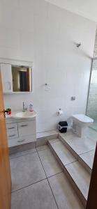 a white bathroom with a sink and a toilet at Apartamento da Dani in Guaratinguetá