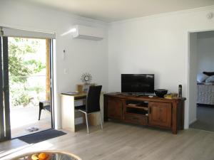 a living room with a television and a desk with a chair at Bay View Retreat Apartment in Whangarei Heads