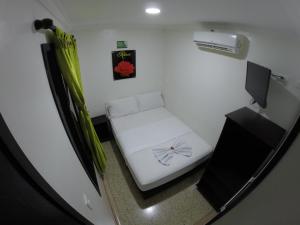 Kleines Zimmer mit einem weißen Bett und einem TV. in der Unterkunft Casa Villavicencio in Villavicencio