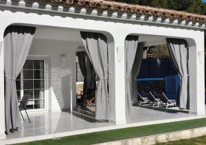 a whiteconservatory with chairs and curtains on a patio at Menorca Villa Marbella in Son Parc