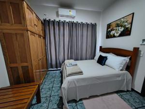 a small bedroom with a bed and a wooden cabinet at Loft Carminatti in Cacoal