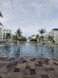 a large swimming pool with palm trees and buildings at Emerald Marina TL in Phú Quốc