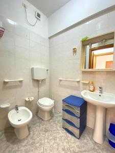 a white bathroom with a toilet and a sink at Bentu e Soli Home Holiday in Villasimius