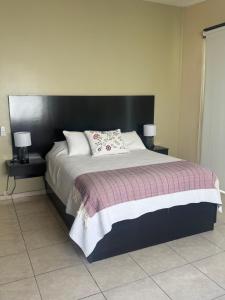 a large bed with a black headboard and two lamps at Beach house in San Miguel, Ensenada in Ensenada