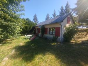 a small house with a red door in a yard at Hôtel Restaurant Le Regimbal in Javols +1 photo