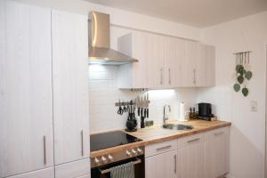 a kitchen with white cabinets and a sink at Green Mango - City Apartment mit Balkon in Mürzzuschlag