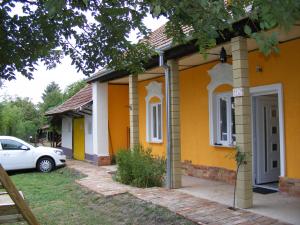 a yellow house with a car parked in front of it at Négy Gólya in Sarud
