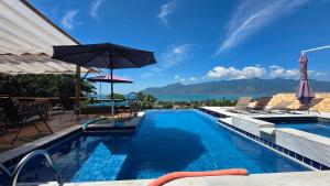 a swimming pool with an umbrella and a view of the ocean at Studio Moderno com Vista pro mar com hidromassagem e churrasqueira privativas e Piscina aquecida na área comum in São Sebastião