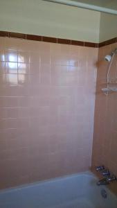 baño con bañera y pared de azulejos rosas en White Sands Motel, en Alamogordo