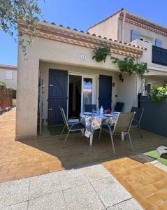 a patio with a table and chairs and a house at 4HTAMA5-Charmante maisonnette avec terrasse in Le Barcarès