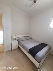 a white bedroom with a bed and a night stand at Almaza bay Beach Town Chalet in Marsa Matruh
