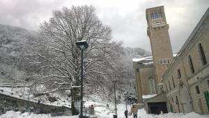 a snow covered tree next to a building with a clock tower at Light Home in Avellino