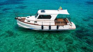 a white boat floating in the clear blue water at Che Manovra - A Night Onboard! in Porto San Paolo +5 photos
