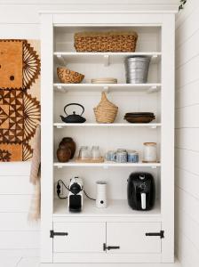 a white pantry with dishes and baskets on the shelves at Beach HideAway in Noordwijkerhout
