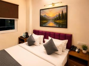 a bedroom with a bed with a painting on the wall at Hotel Stayzzy Bloom in Noida