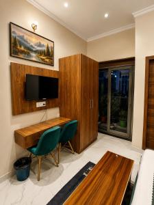 a living room with a wooden desk and a tv at Hotel Stayzzy Bloom in Noida +34 photos