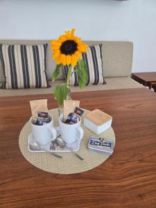 a table with two cups and a vase with a sunflower at Ferienwohnung mit kleinem Garten in Nettersheim