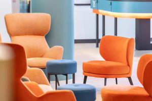 a row of chairs with orange and blue seats at Hey Lou Hotel Friedrichshafen in Friedrichshafen