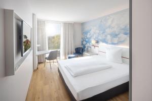 a bedroom with a white bed and a desk at Hey Lou Hotel Friedrichshafen in Friedrichshafen