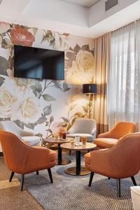 a living room with chairs and a wall with flowers at Hey Lou Hotel Karlsruhe Messe in Karlsruhe