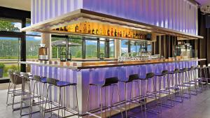 a purple bar with stools in a room with windows at Hey Lou Hotel Monheim am Rhein in Monheim