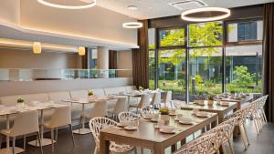 a dining room with tables and chairs and windows at Hey Lou Hotel Monheim am Rhein in Monheim