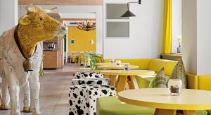 a cow statue in a restaurant with tables and chairs at Hey Lou Hotel Piding in Piding +28 photos