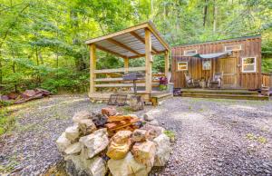 a cabin in the woods with a grill and a pile of logs at Shiners Shack in Newport