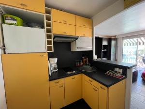 a small kitchen with yellow cabinets and a sink at Studio Bandol Port in Bandol