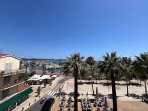 a street with tables and palm trees in a city at Studio Bandol Port in Bandol