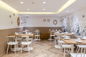 a dining room with wooden tables and white stools at Hotel Magenta 38 by Happyculture in Paris