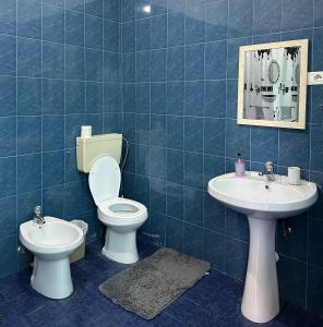 a blue tiled bathroom with a toilet and a sink at Guest House by Roni in Durrës +99 photos