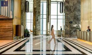 a woman walking through a lobby with large windows at Landmark 81 Exclusive Panorama Residence in Ho Chi Minh City