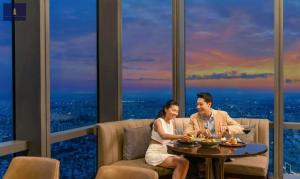 a man and a woman sitting at a table in a restaurant at Landmark 81 Exclusive Panorama Residence in Ho Chi Minh City