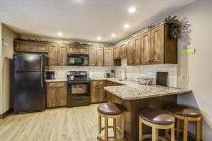 a kitchen with wooden cabinets and a black refrigerator at Tannhauser 222 in Breckenridge