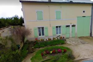 a house with green shutters and a garden with flowers at Gîte Saint Gorgon in Euville