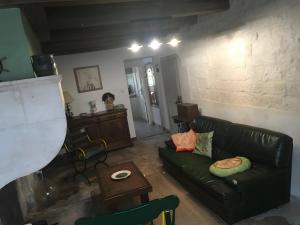 a living room with a black leather couch and a table at Gîte Saint Gorgon in Euville